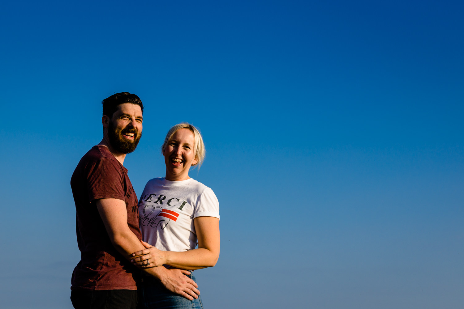 A couple laugh together on their sunny shoot in Anglesey.