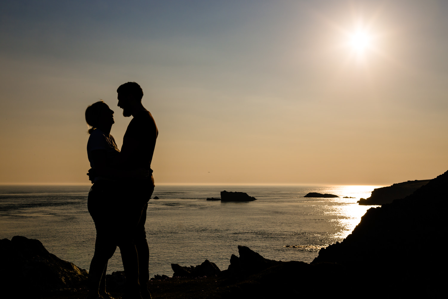 A couple's silhouette against the golden hour sunset on a pre wedding shoot, Anglesey wedding photography