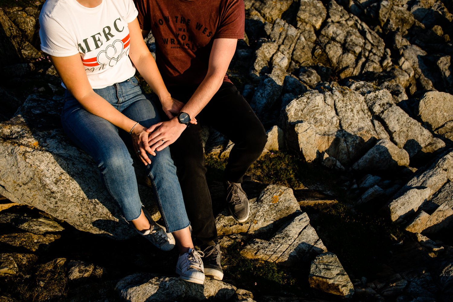 Detail of a couple holding hands sat on the Anglesey headland.