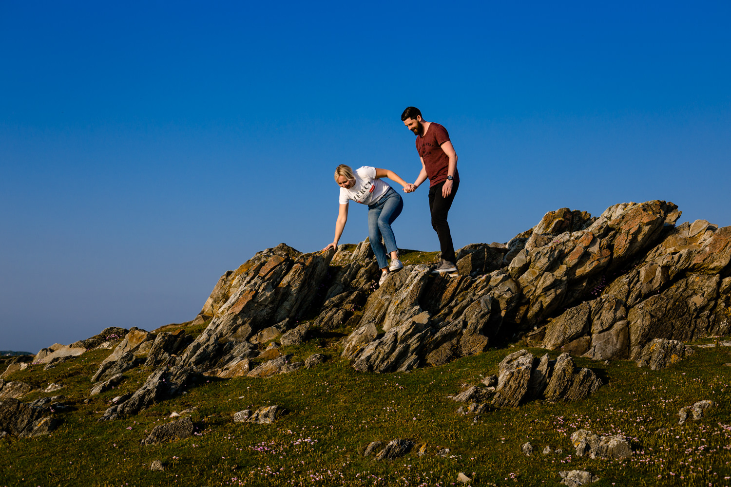 Katie & Sean climb over the rocks on a pre wedding shoot in Anglesey.