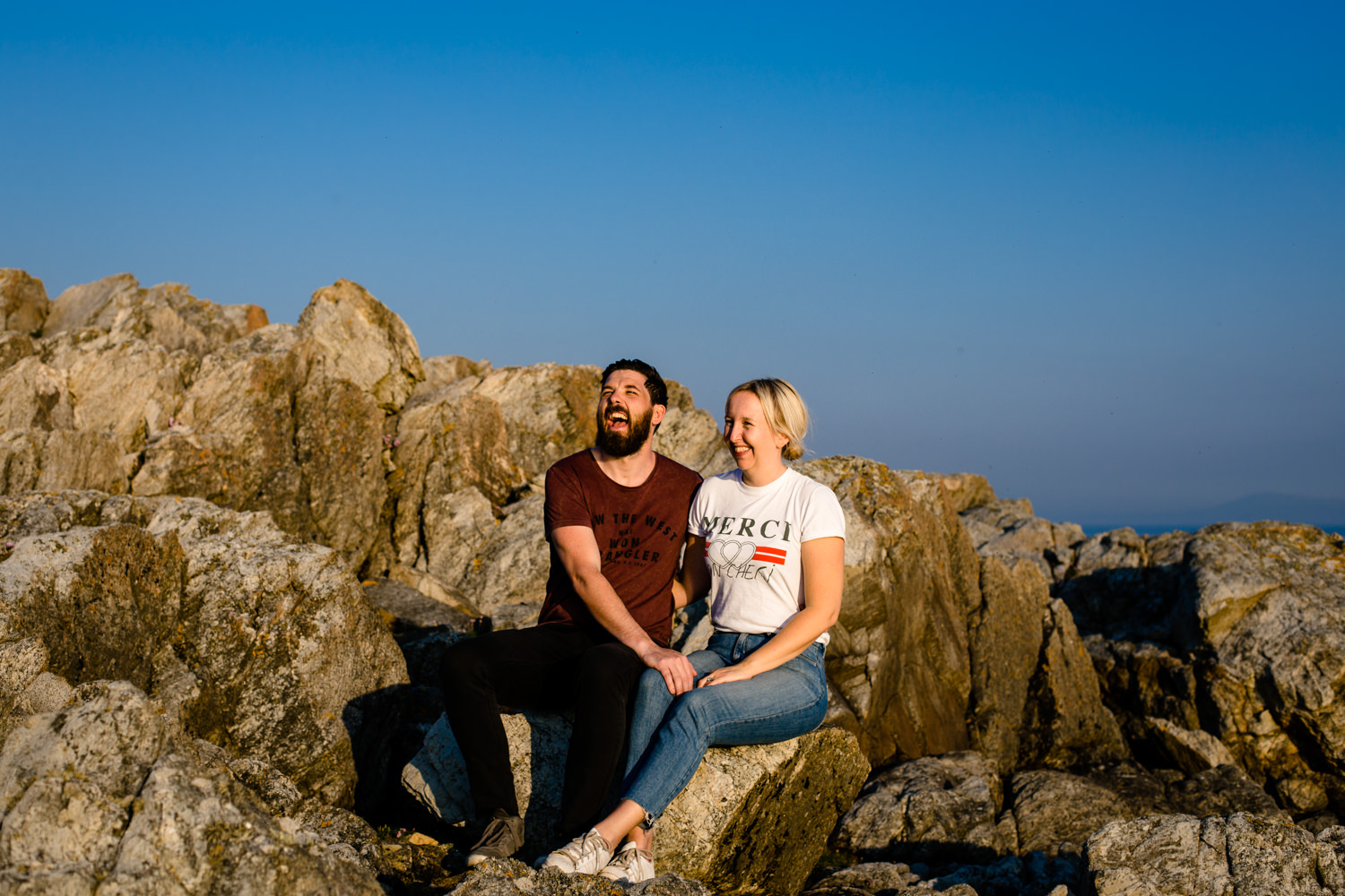 Laughing couple on a fun and relaxed pre wedding shoot in Anglesey. 