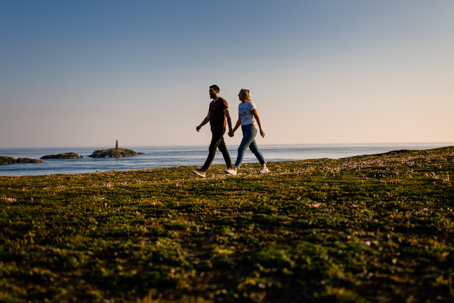 Walking couple on the headland over looking the sea in Anglesey, Wales. 