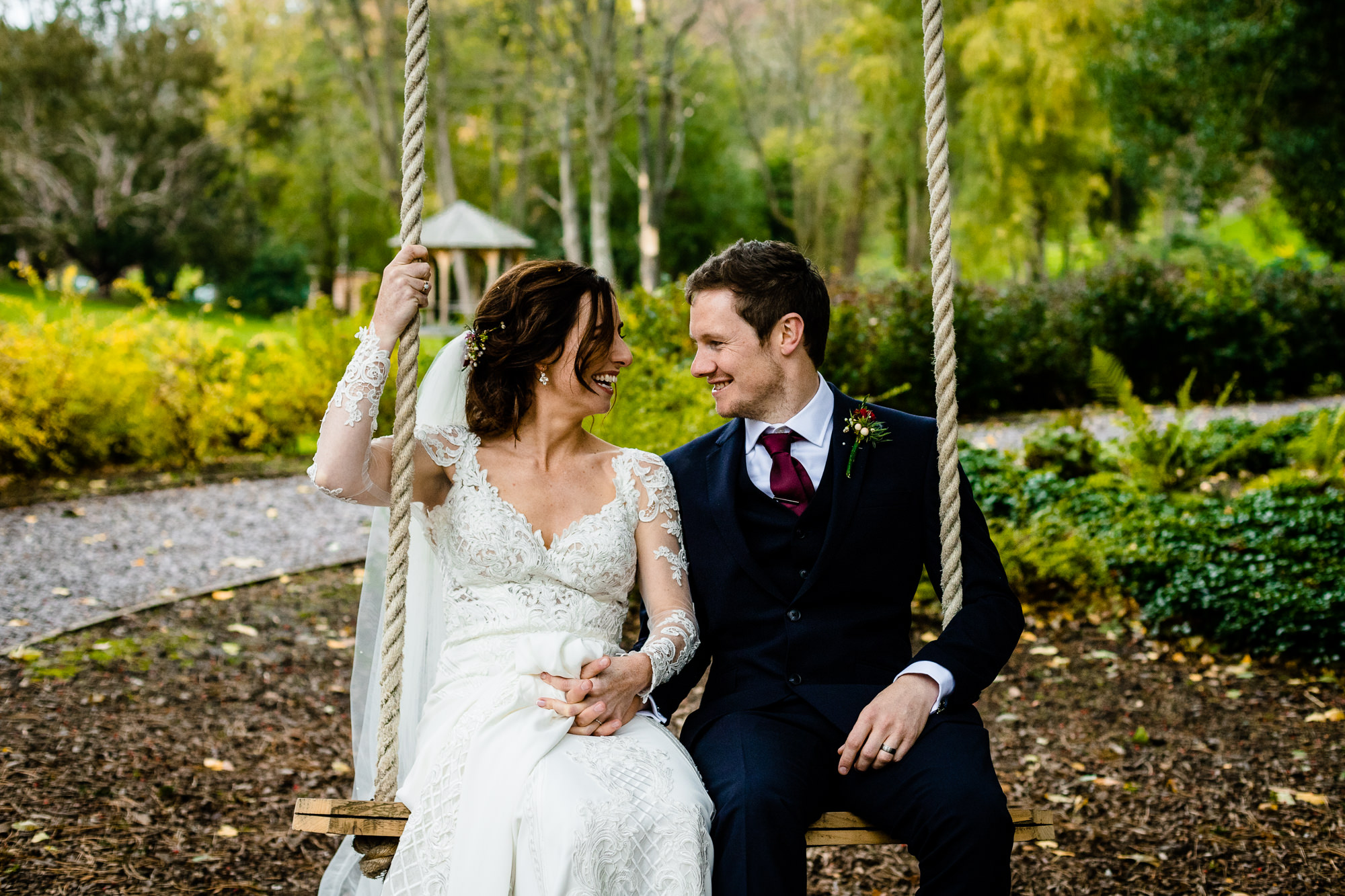 Bride and Groom sat on a swing in woodland in Wales