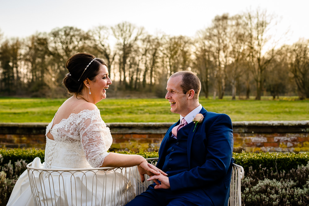 Kate and Paul sit and laugh together at sunset in the gardens at Iscoyd Park on their wedding day by wedding photographer About Today Photography. 