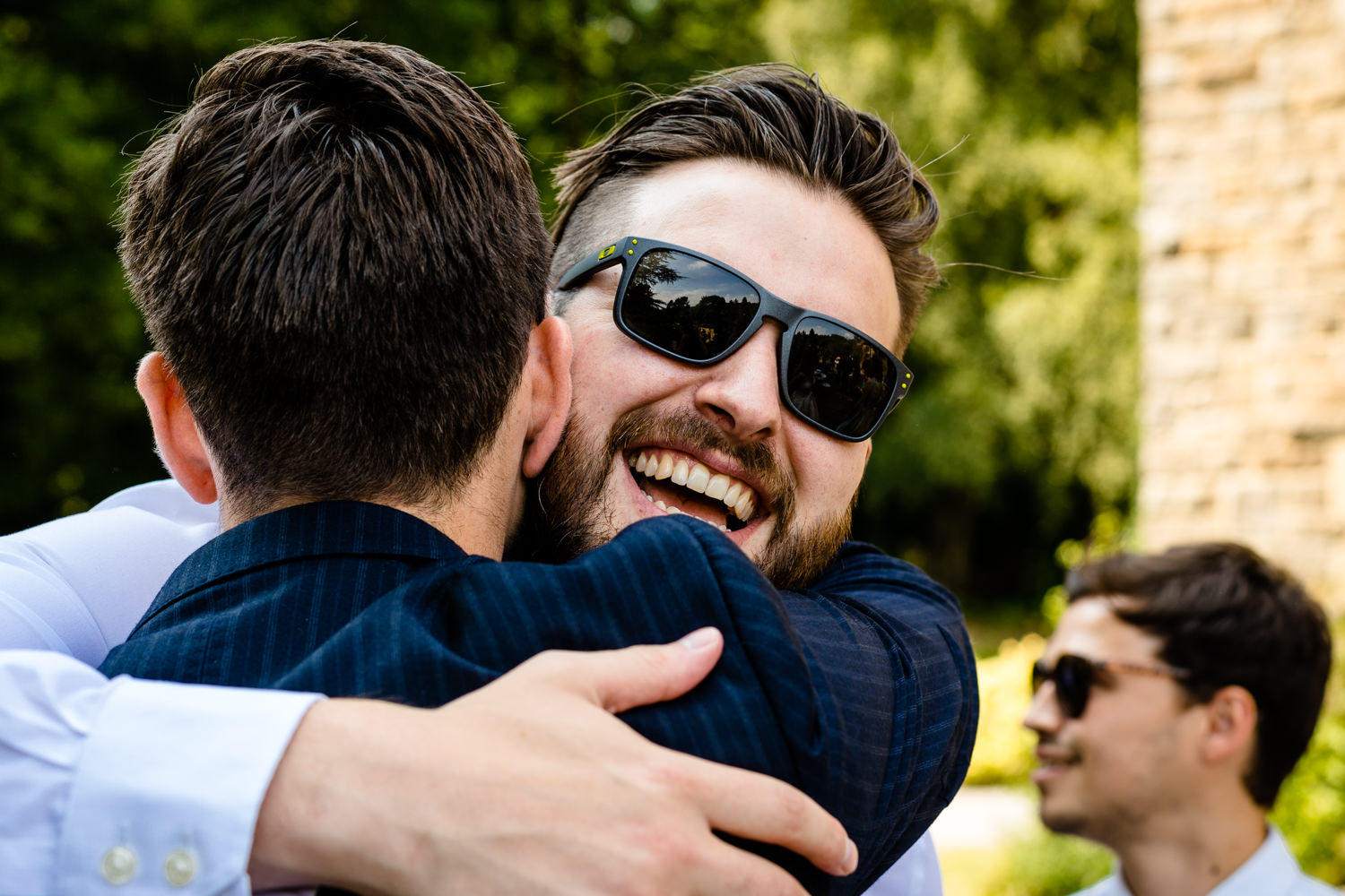 A guest smiling and hugging the groom.