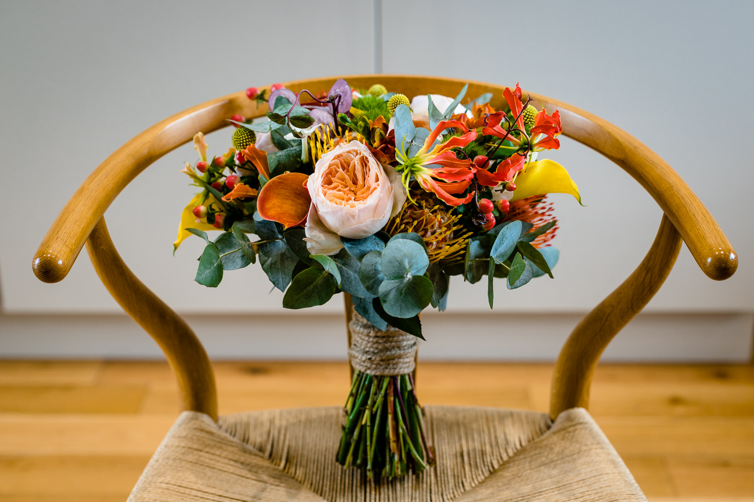 Colourful bouquet on a wishbone chair, Anglesey wedding photography