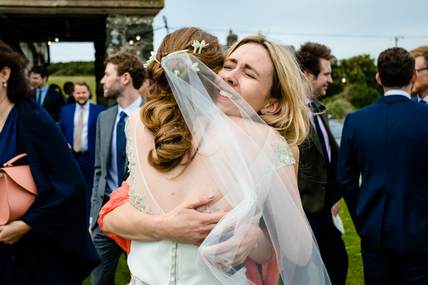A guest hugs the bride, relaxed Anglesey wedding photographer