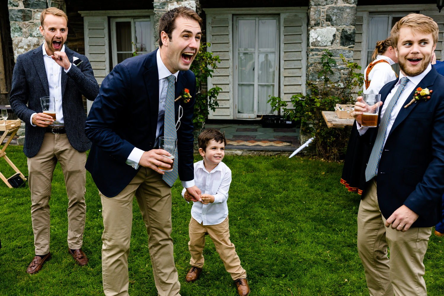 A groomsman laughing at what a young boy  has said, relaxed Anglesey wedding photo