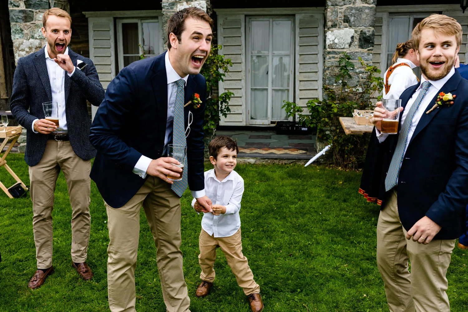 A groomsman laughing at what a young boy has said, relaxed Anglesey wedding photo