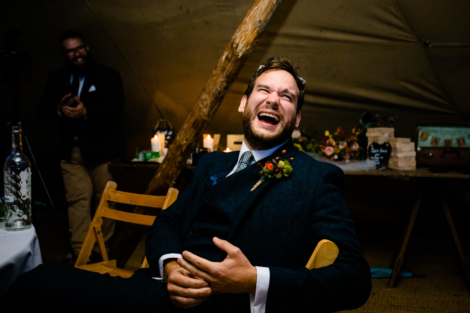 A groom laughs at his best mans speech, relaxed Anglesey wedding photos