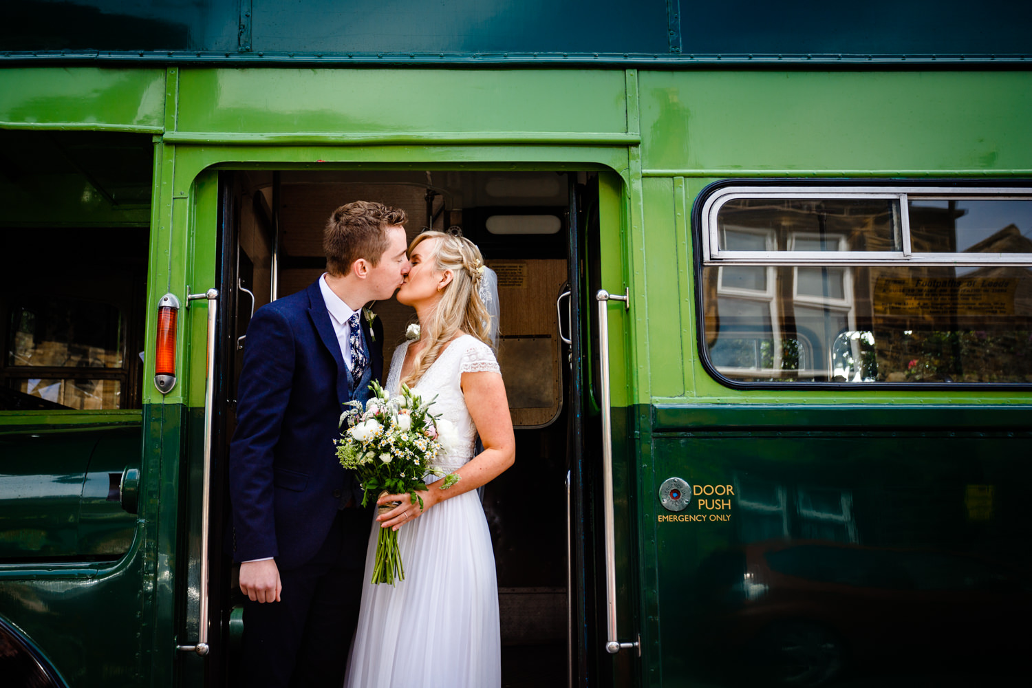 Huddersfield Wedding Photographer, a bride and groom kiss in front of their colourful green vintage bus on their way to Northorpe Hall Barn