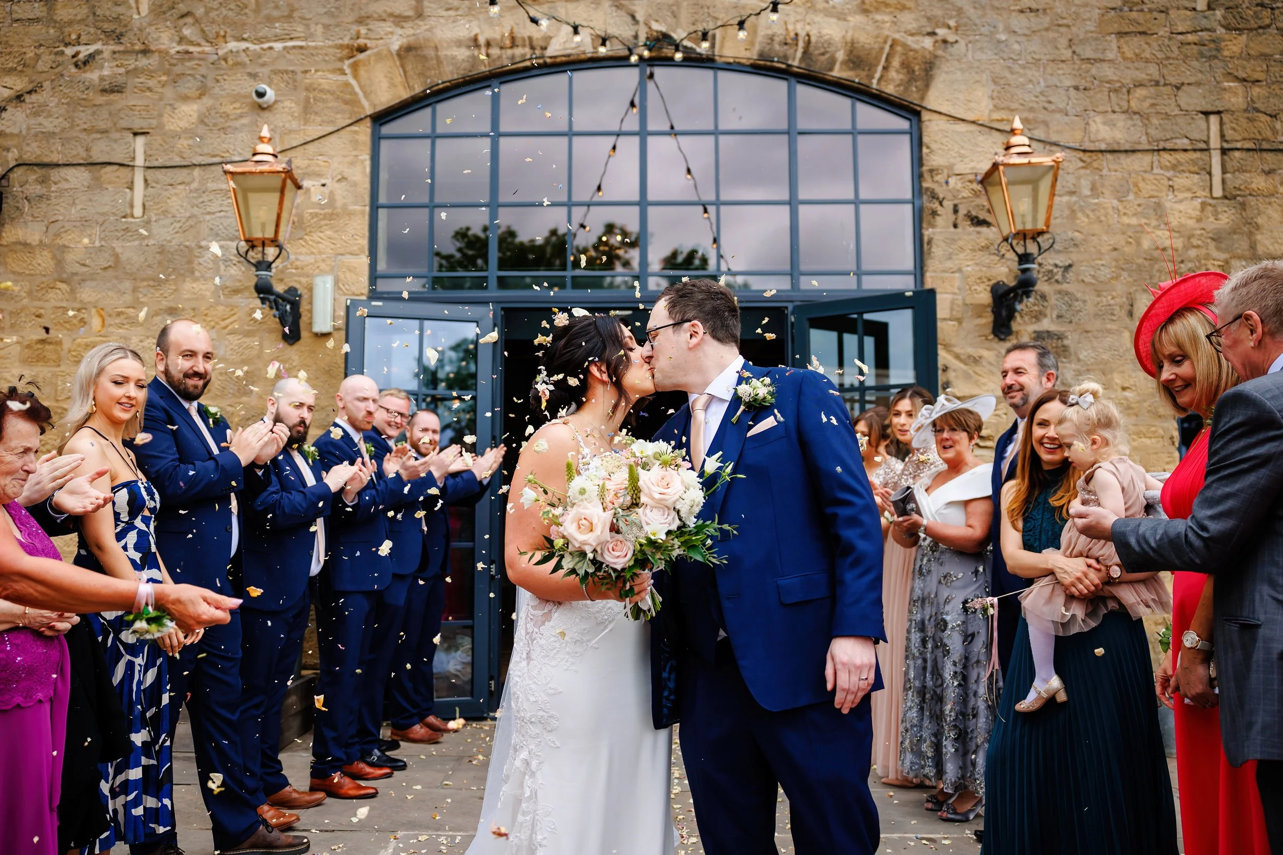 Bride and groom kiss under confetti at their Wharfdale Grange Wedding