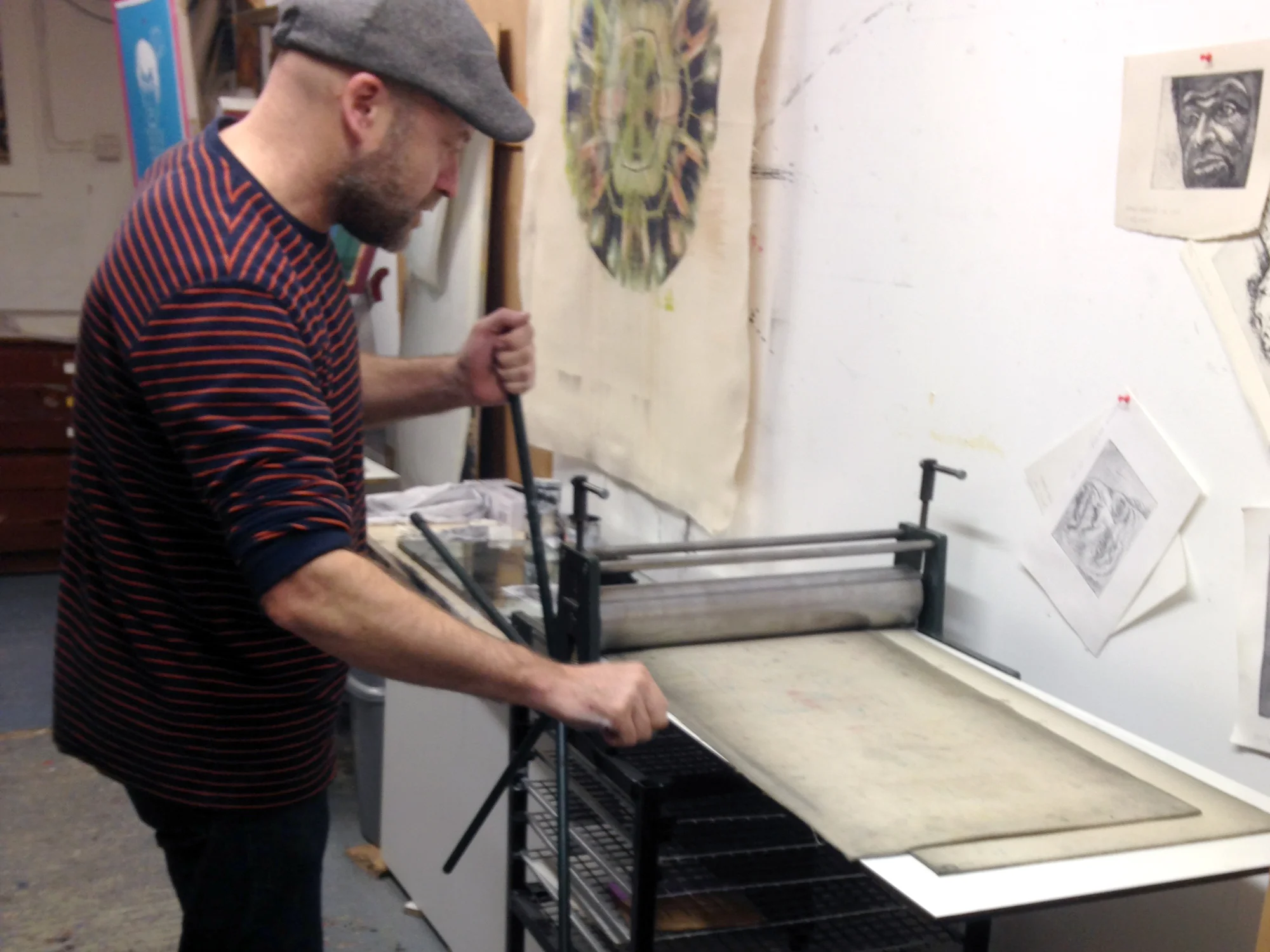 The plate is put through a high-pressure printing press together with a sheet of paper (moistened to soften it). The paper picks up the ink from the etched leaf, making a print