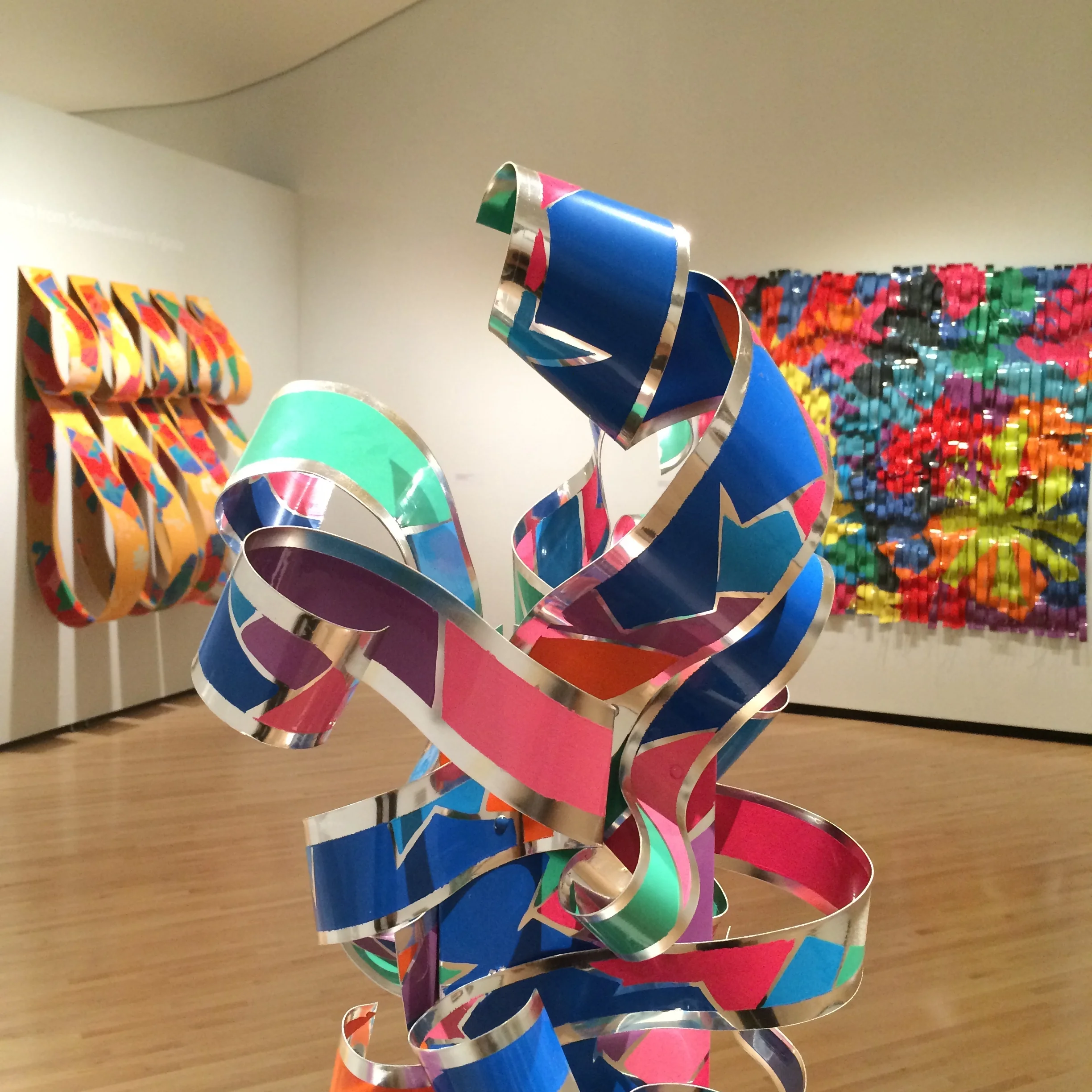 Enamel on aluminum works by Roanoke artist Dorothy Gillespie in Legacies: Honoring Artistic Luminaries from Southwestern Virginia at the Taubman Museum of Art. Foreground: Ribboned Presence , 1993. Rear left: Tiered Arrangement III . Rear right: Colorfall Series, Garden , 1993.
