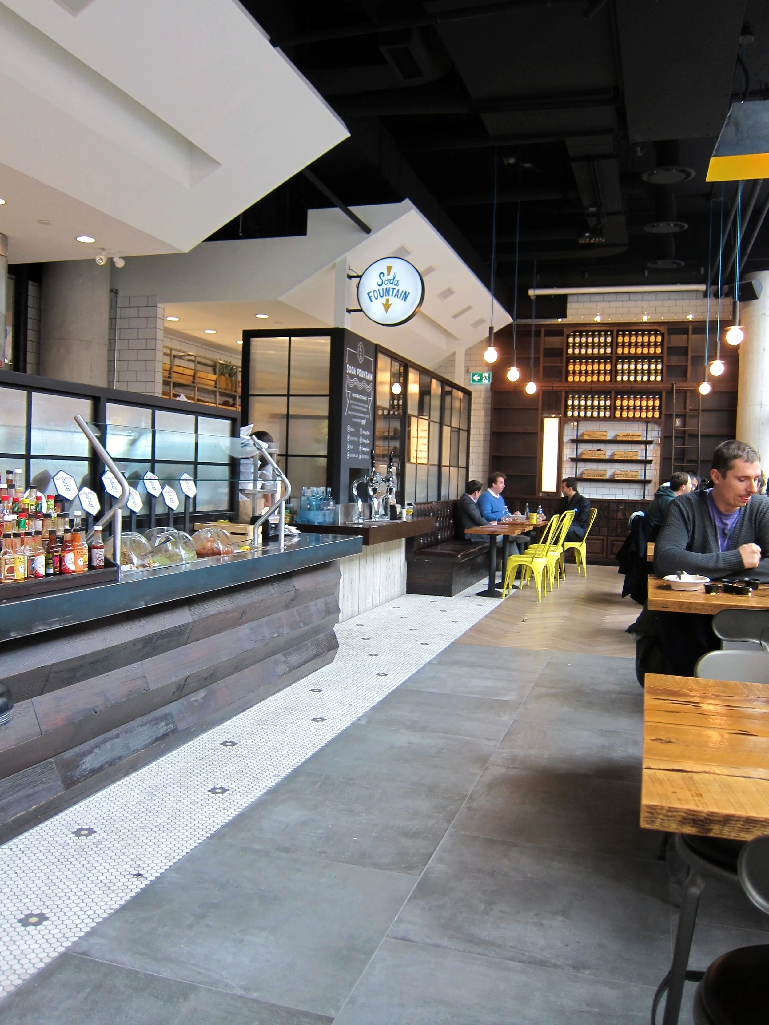 Picture of accessible interior of restaurant. Wide pathway between cash counter and tables.
