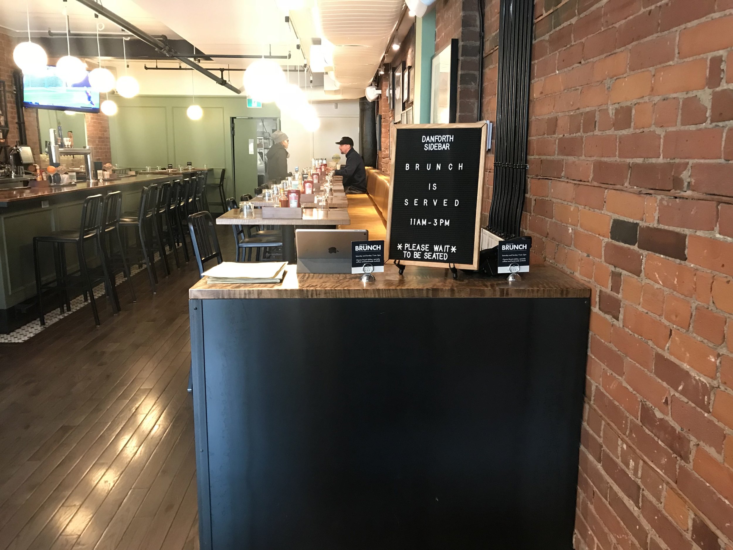 Picture of hostess counter and bar at Sidebar. Wide pathway displayed.