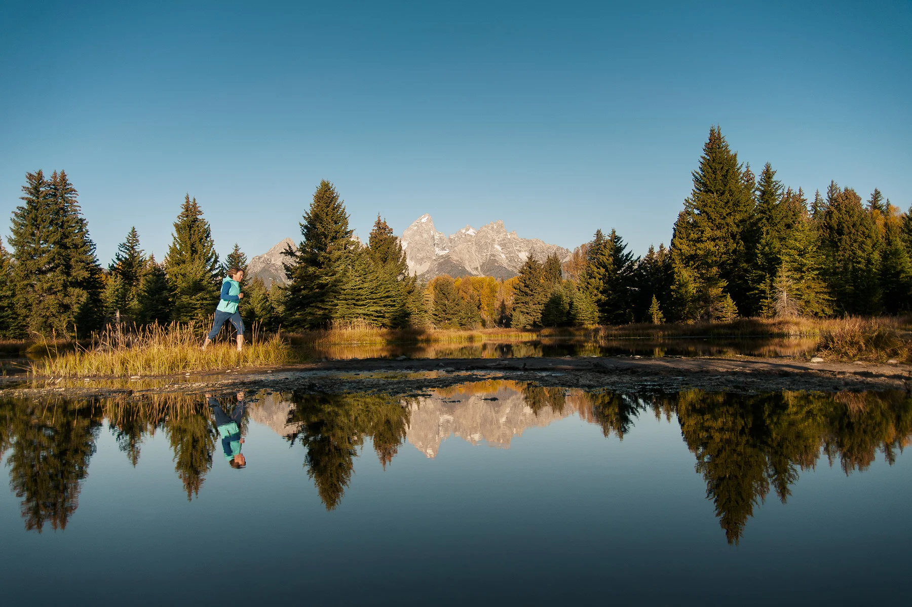 A female athlete running at sunrise in front of the Grand Teton range