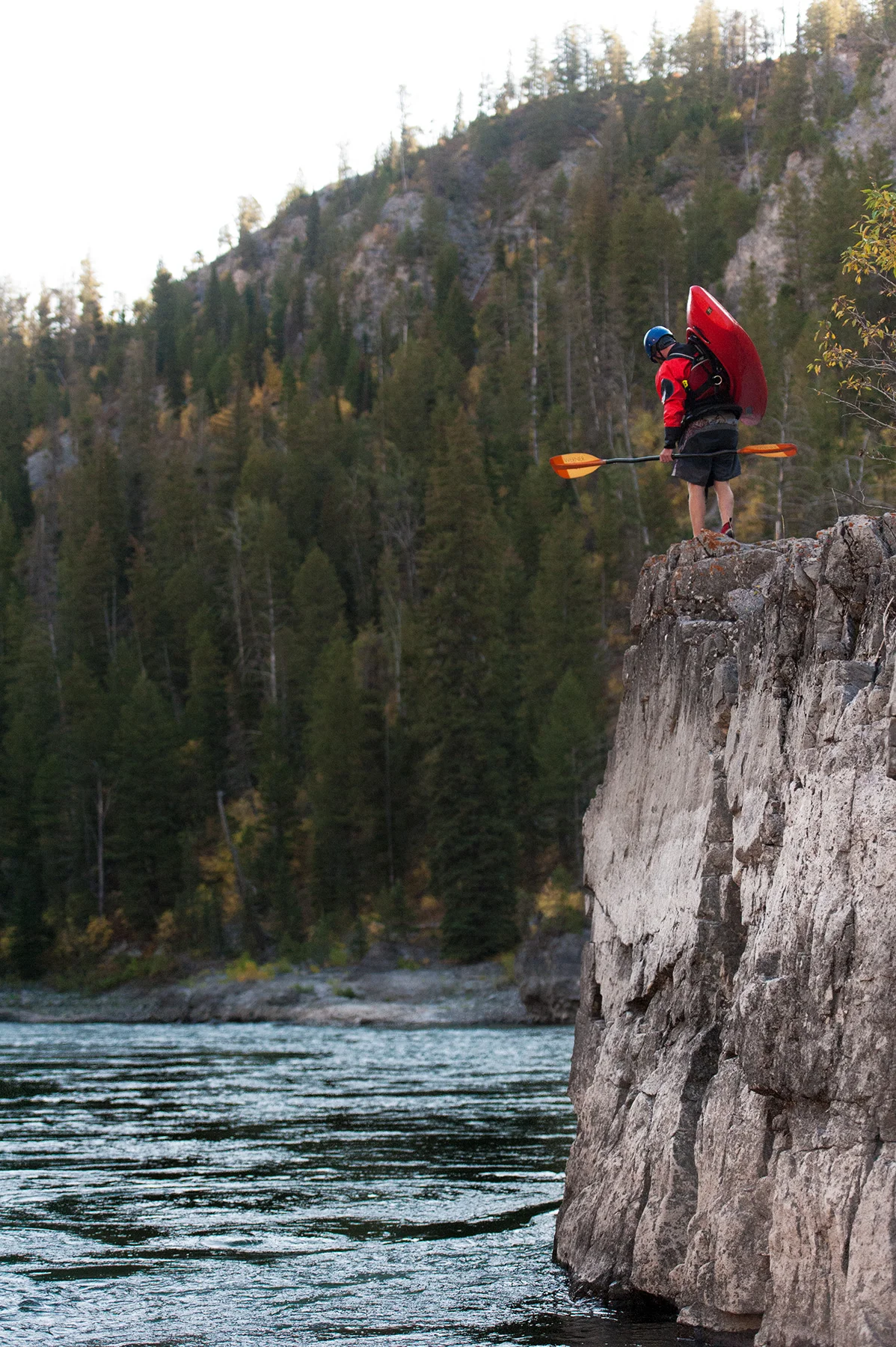 A kayaker walks upstream along the Snake River on a cliff in Wyoming