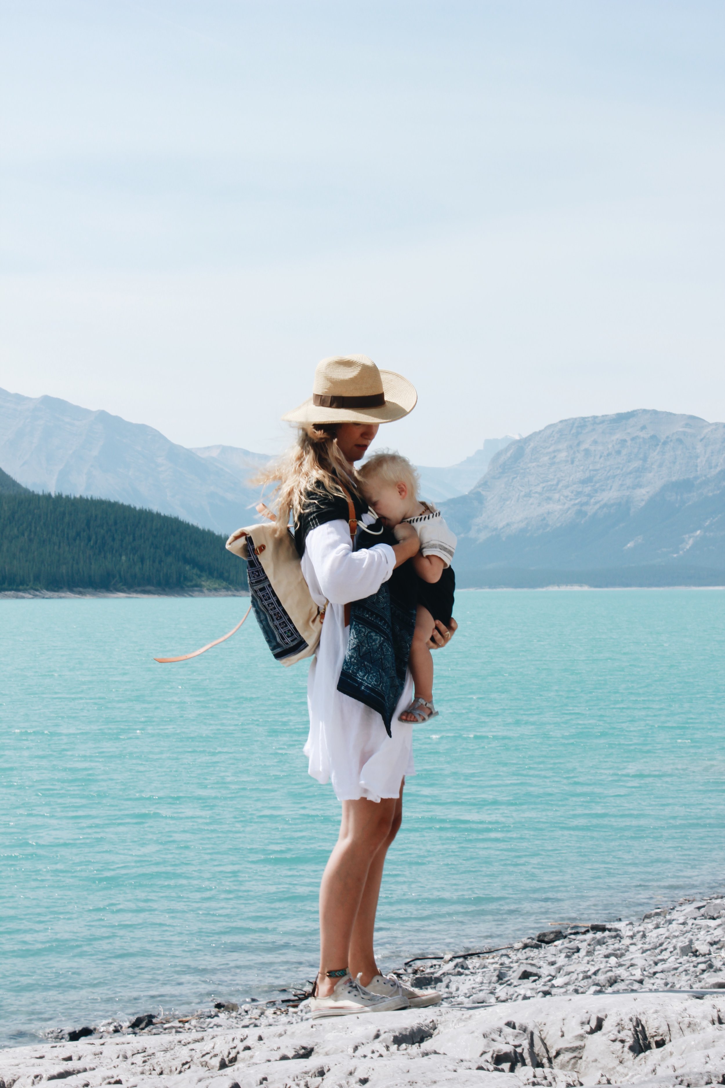 Kristen Adorned in the Kundalini Gown Short . Sawyer is wrapped in the Aura Leaf Co . Sling and rocking the " Myrah Backpack " 