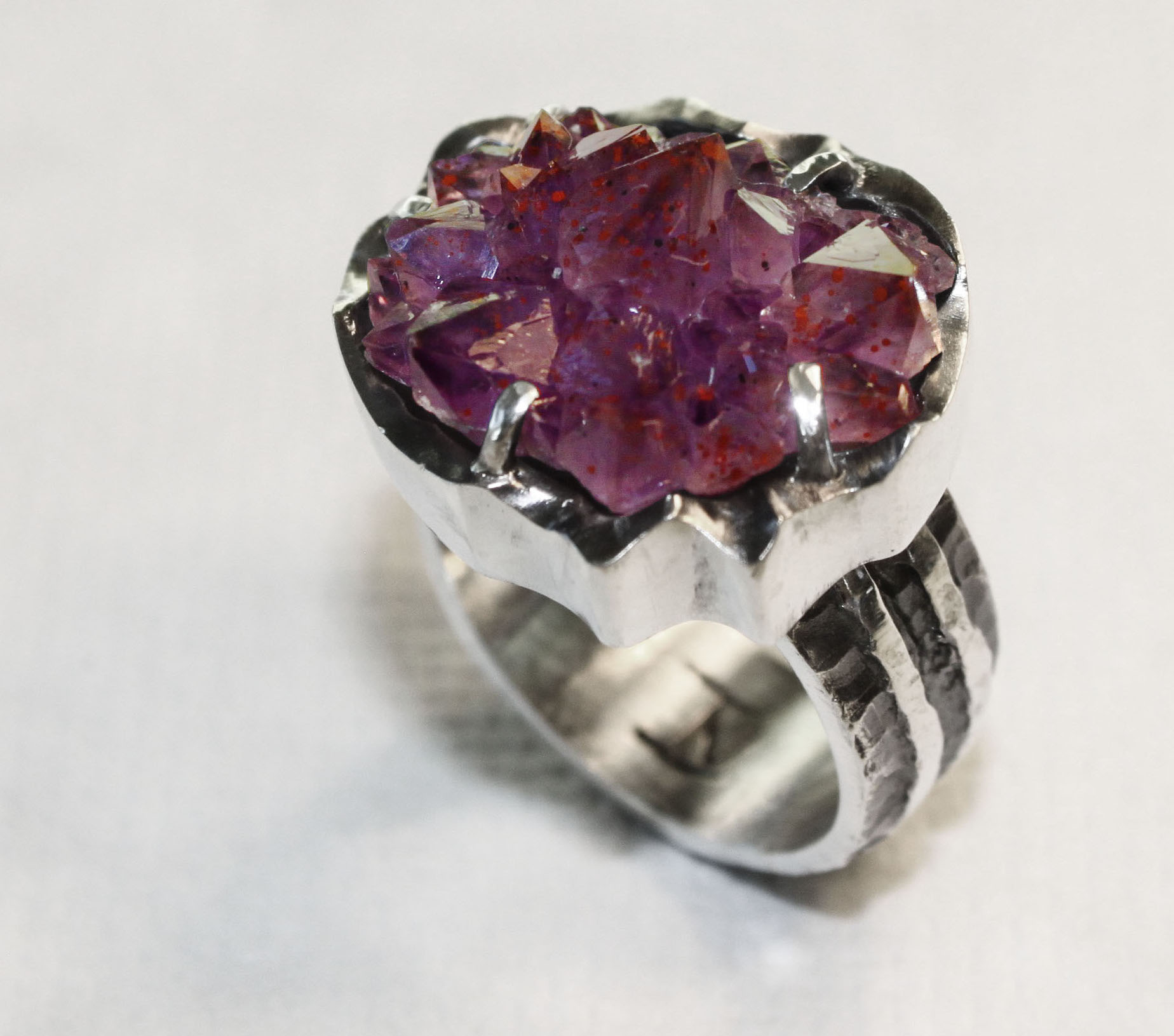Amethyst crystal cluster with hematite inclusions from the Blue Point mine in Pearl, Ontario, Canada. This crystal group in set in a casted sterling silver ring. Available at Echo of the Dreamer, Sedona, Arizona.