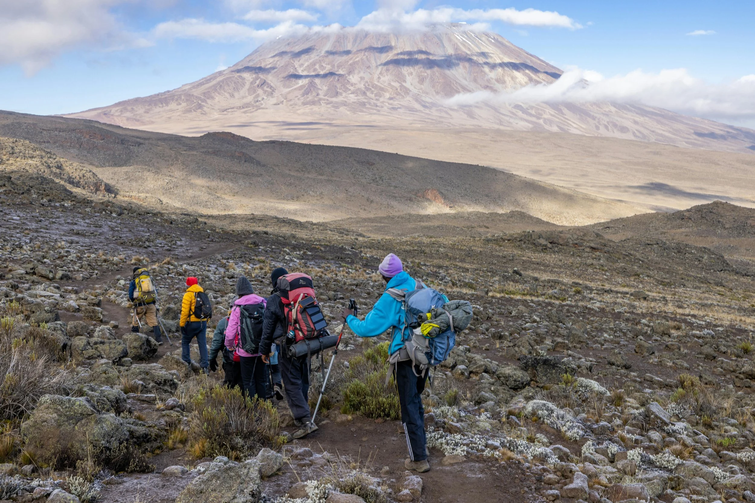A group of hikers climbing Mount Kilimanjaro  throughout its rugged landscapes