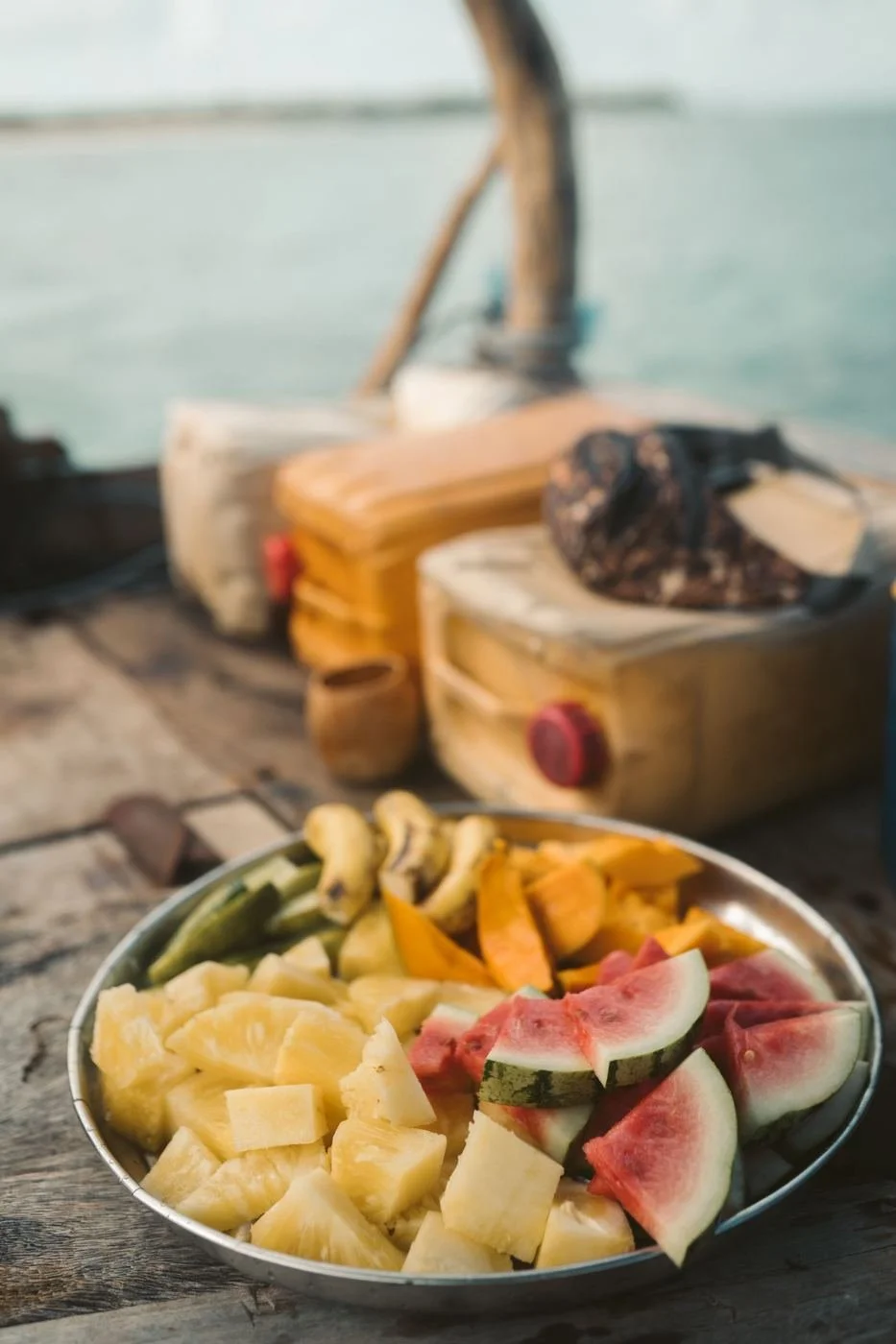 Mangoes, pineapples, watermelon and bananas on a silver plate with the Zanzibar ocean in the background