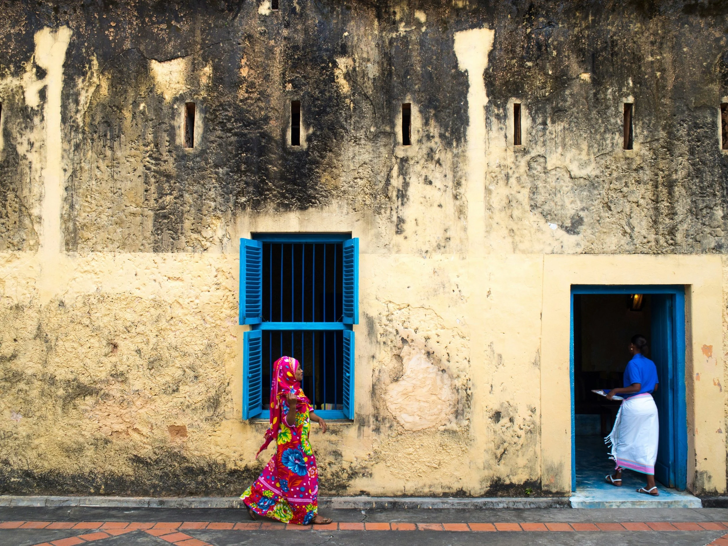 A vibrantly dressed woman walking along the streets of Changu Island in Zanzibar