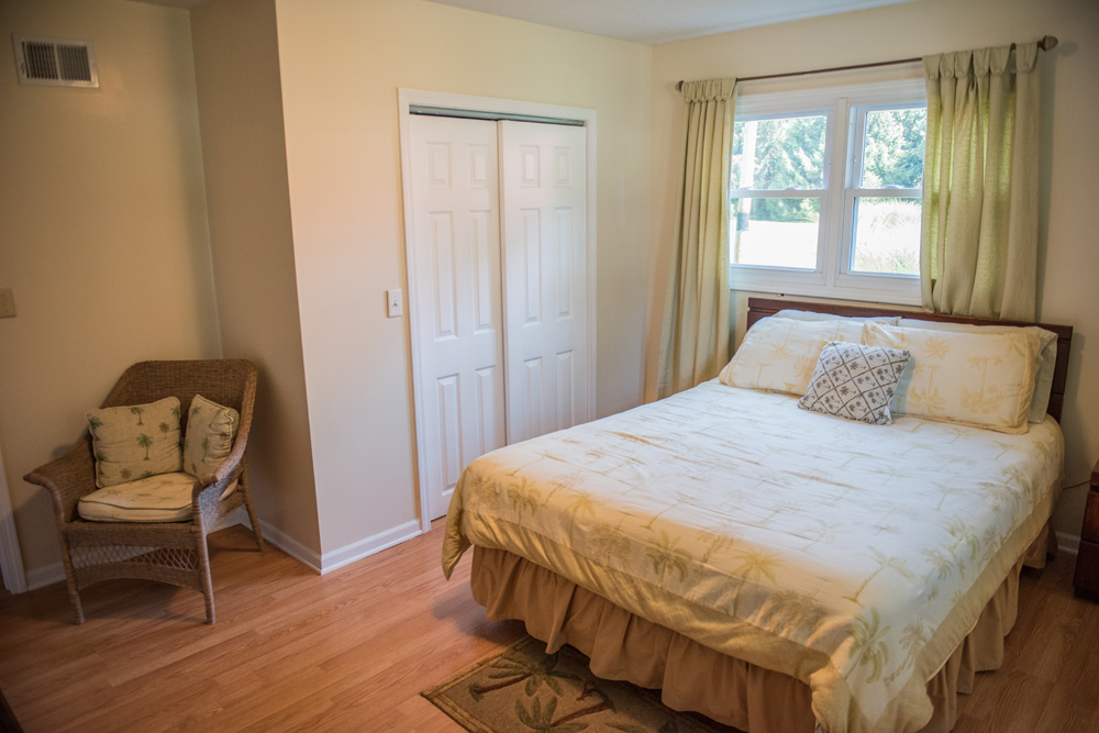 Main bedroom in our cottage with dresser, window and seating area.
