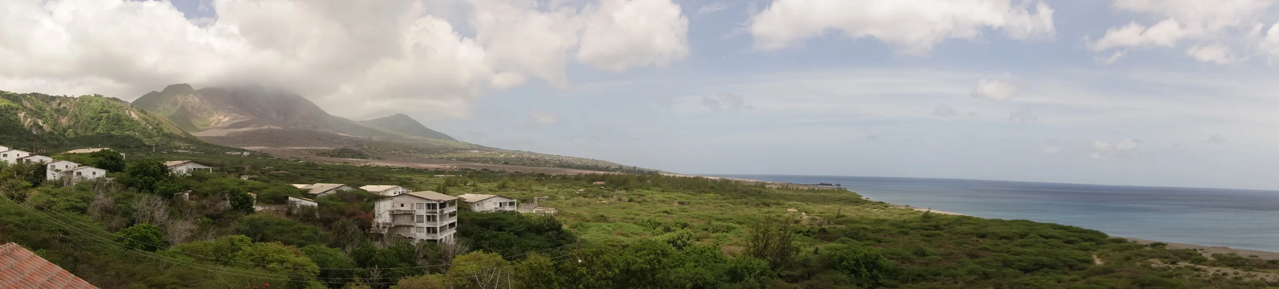 Soufriere hills volcano on the left and the devastated town of Plymouth on the right running to the coast