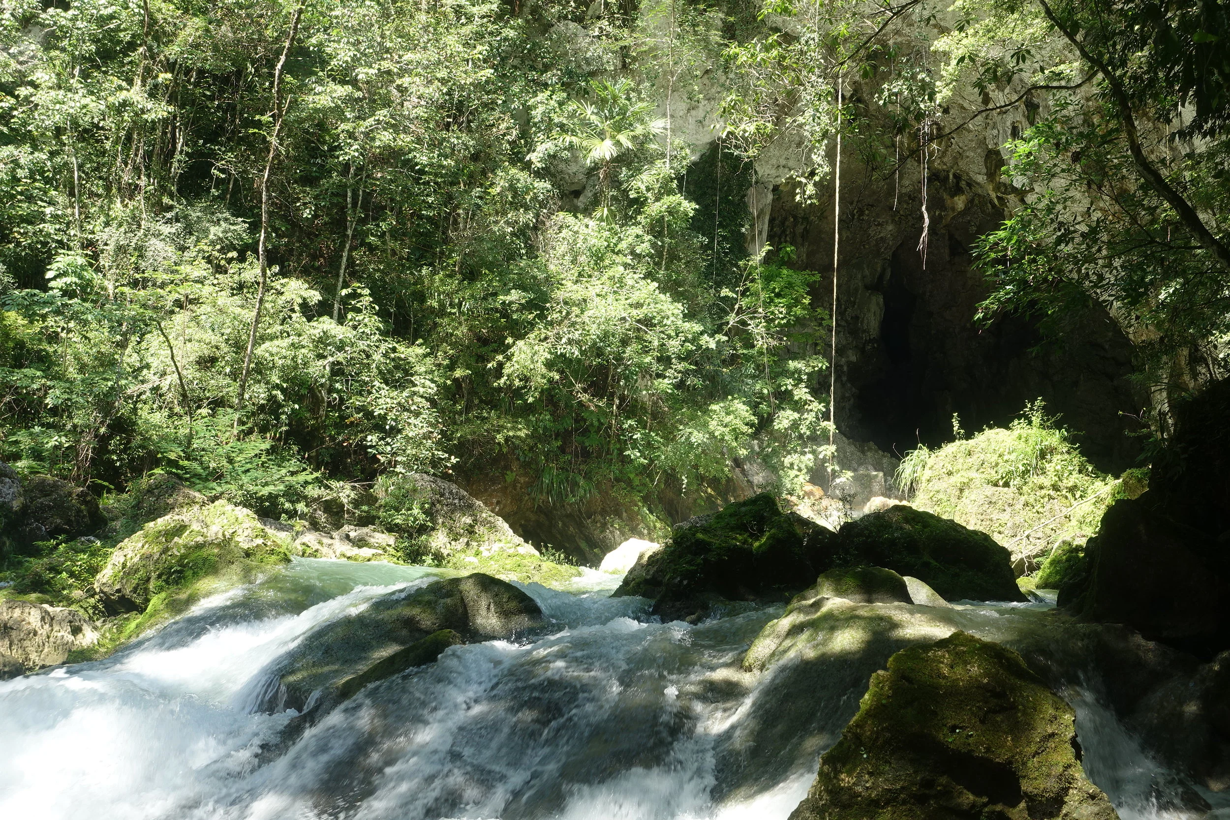 blue creek with the cave entrance in the background