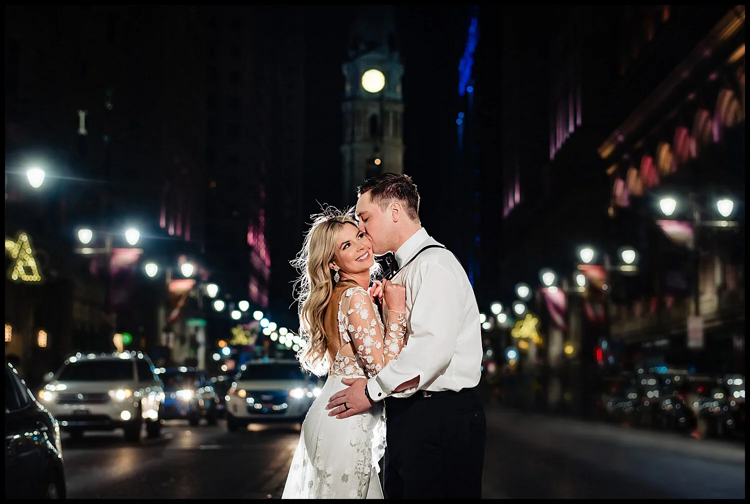 Christina and Ricky kissing on Broad Street at night, City Hall behind them