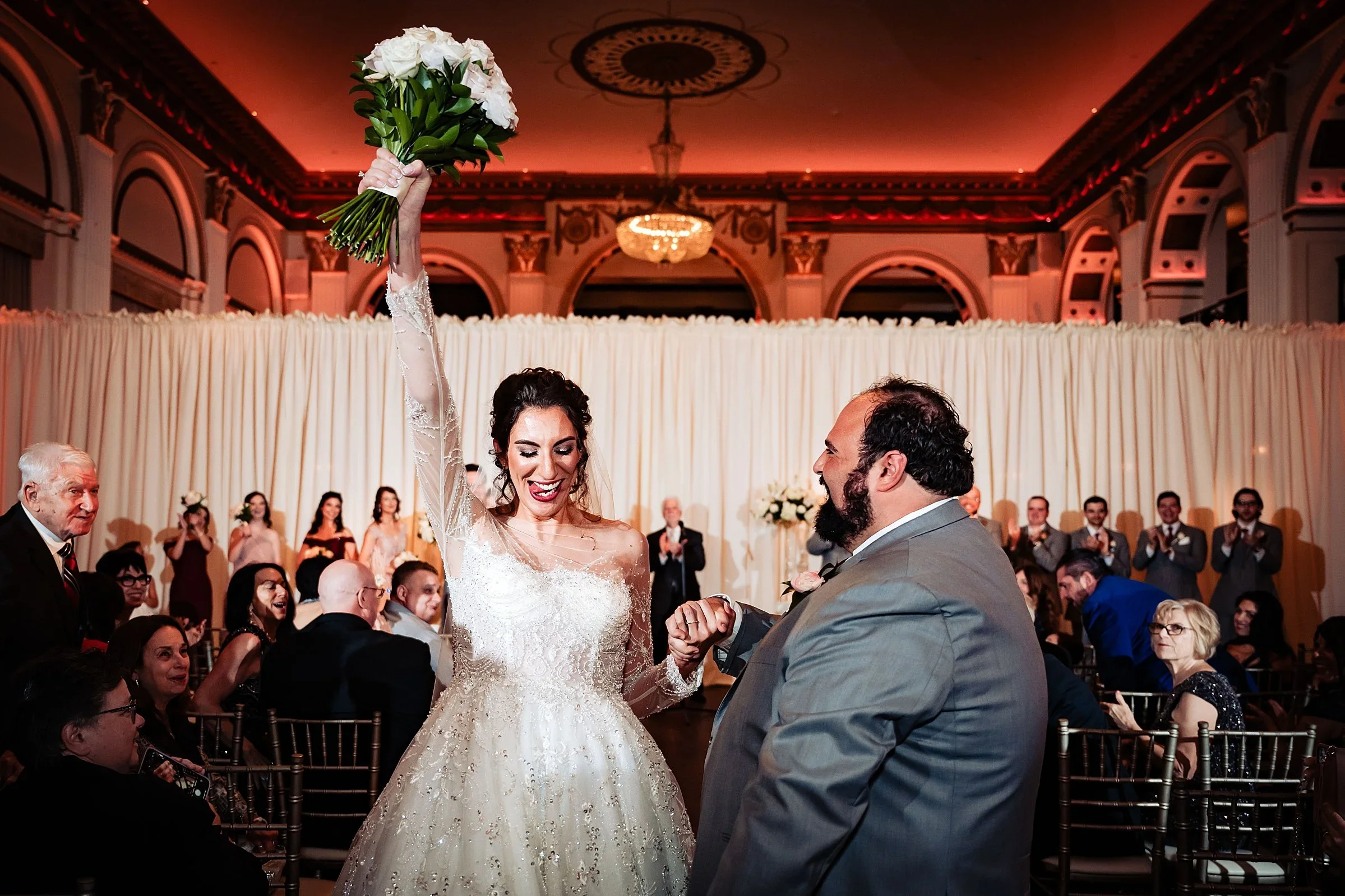 Bride raising her bouquet after the ceremony at Ballroom at the Ben