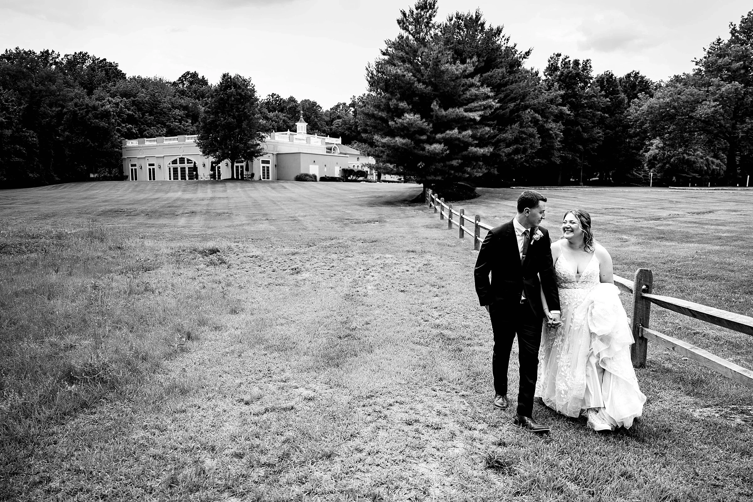 Couple walking along the fence line, the Pen Ryn Mansion in the distance