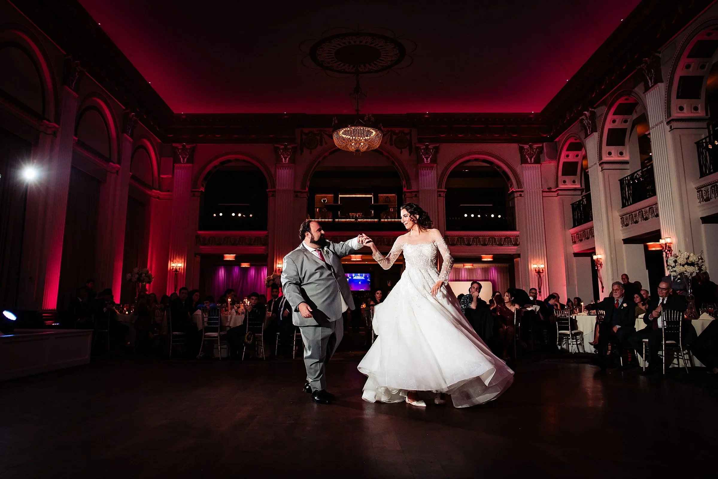 Couple dancing under red uplighting in the ballroom at Ballroom at the Ben