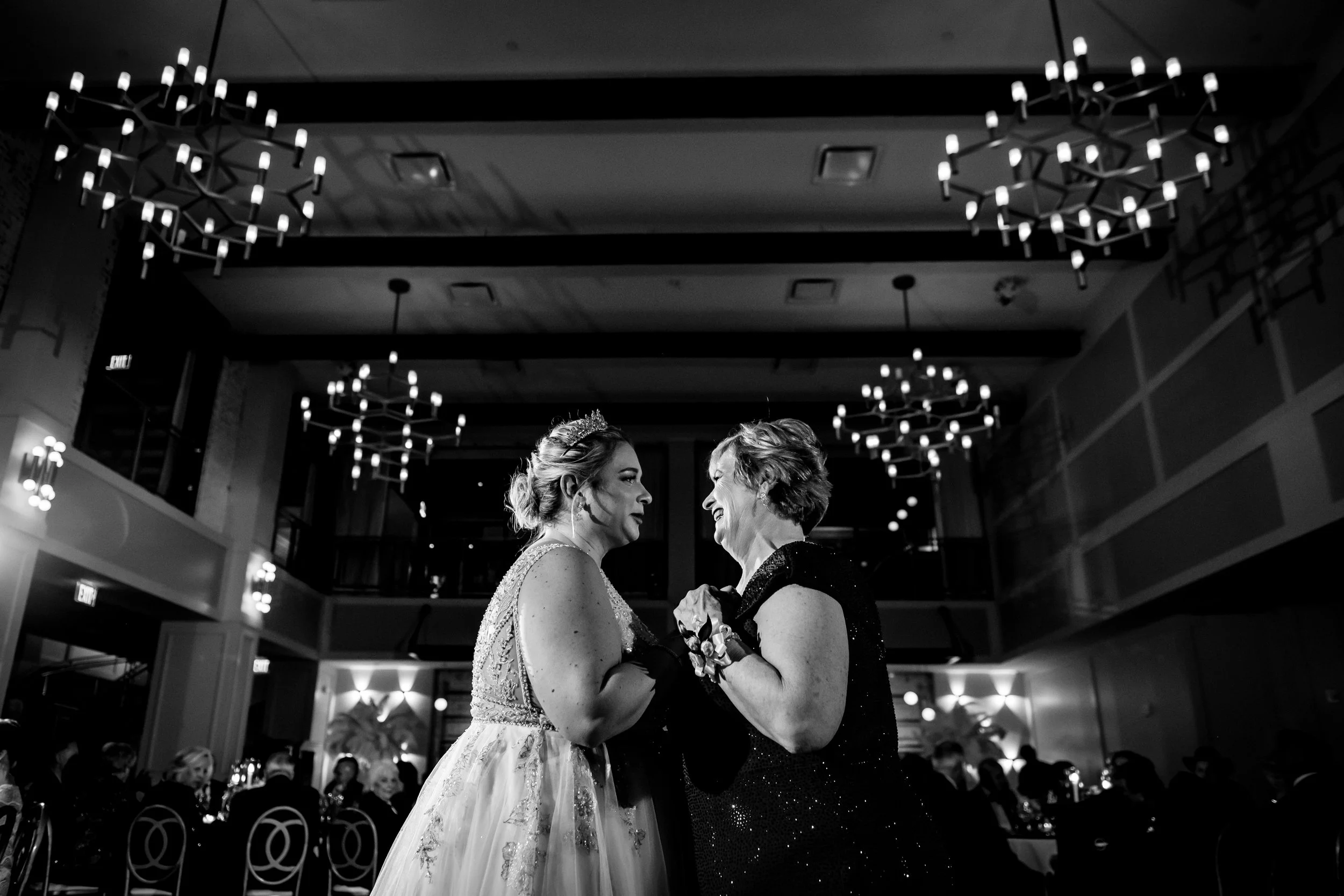 Bride dancing with a guest under the chandeliers at The Lucy