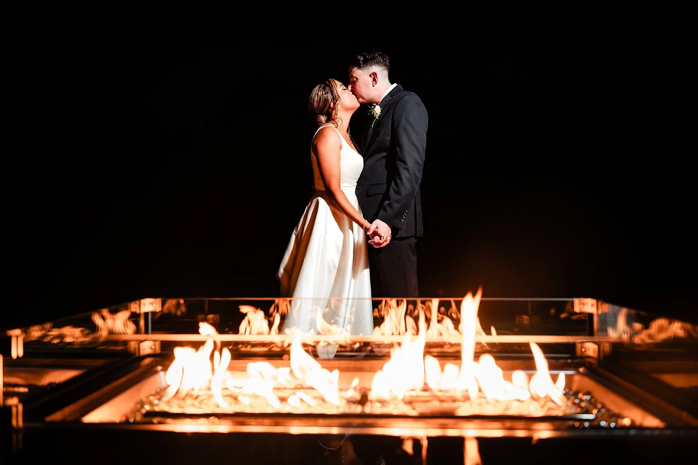 Couple kissing behind a fire pit at night at Pen Ryn Estate