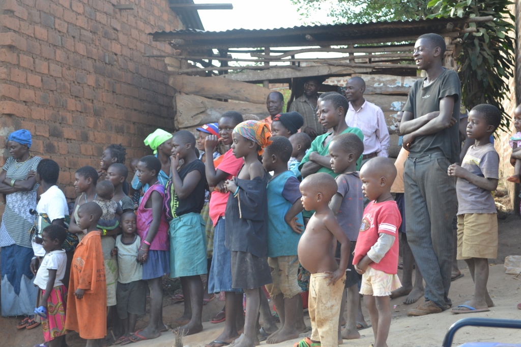 Katuuso village children and community members watch on as Raising Voices run their outreach program.