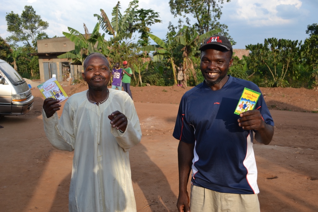 Two Katuuso community members take home pamphlets with information on child abuse and women's rights after the outreach program.