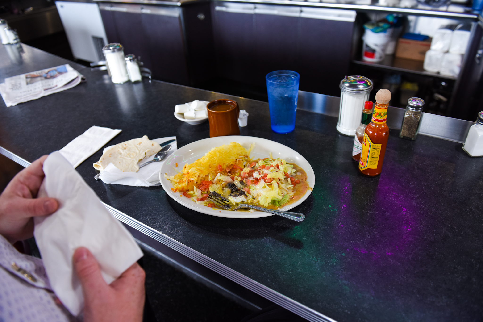 Noon: An out-of-towner, Drew, prepares to eat huevos rancheros. He recently moved from Los Angeles to Asheville, North Carolina, and was in Denver to see his friend's store, Grassroots Colorado, but first stopped at the diner for lunch.