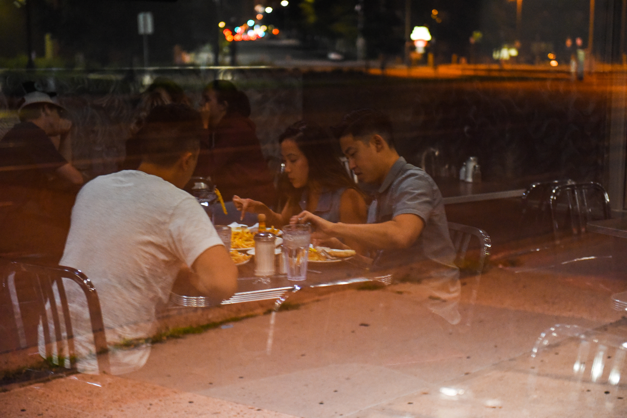 The reflection of a group at a table digging into their food.