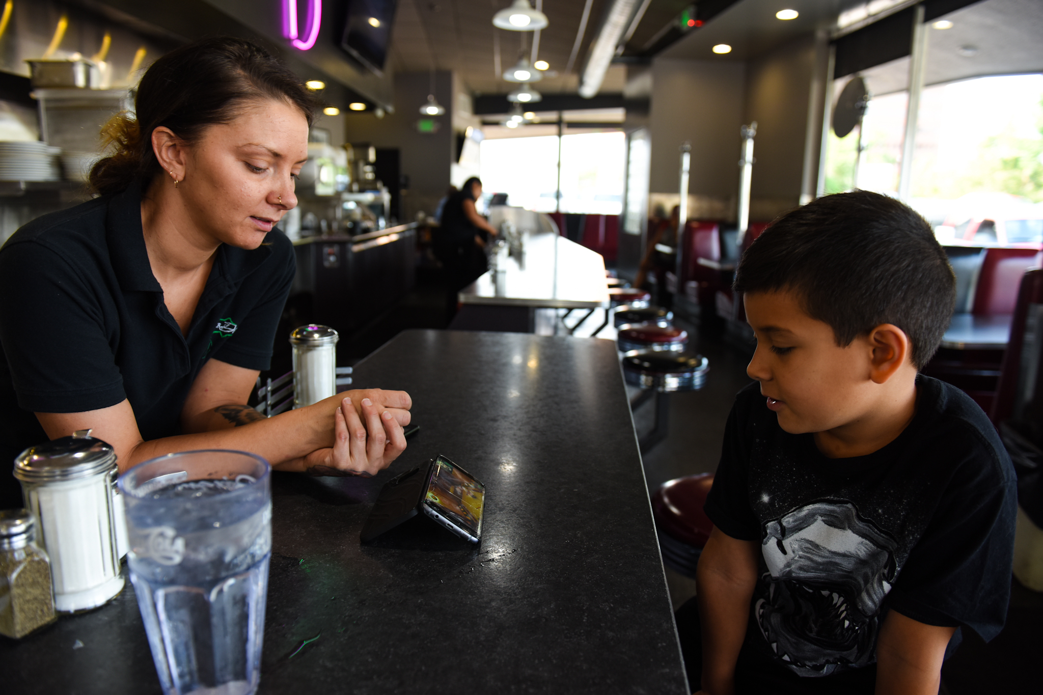 8 a.m: Brittany Graham checks on her son, nine-year-old Gabriel, while he watches a game on YouTube. Brittany has worked at the diner for five years.