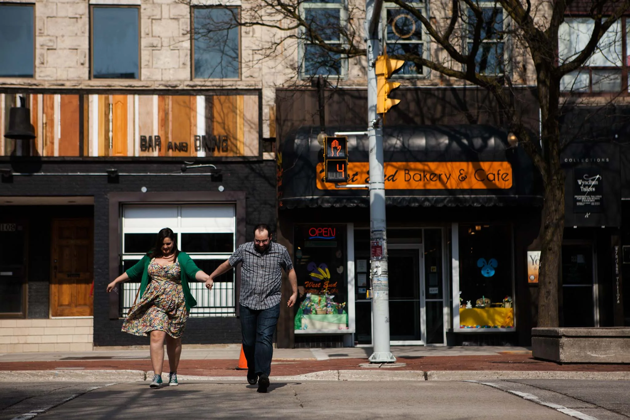 couple holding hands crossing the street during engagement photography session in Guelph.jpg