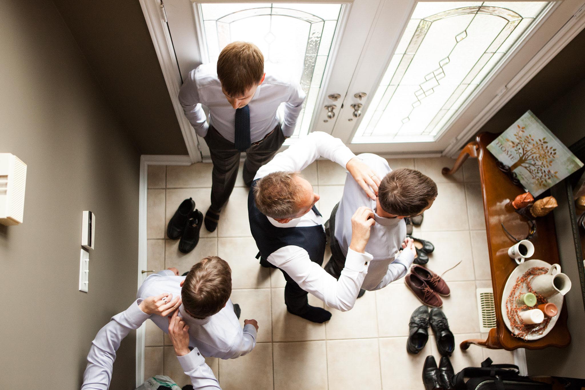 father of the groom helping groomsmen get ready for wedding day.jpg