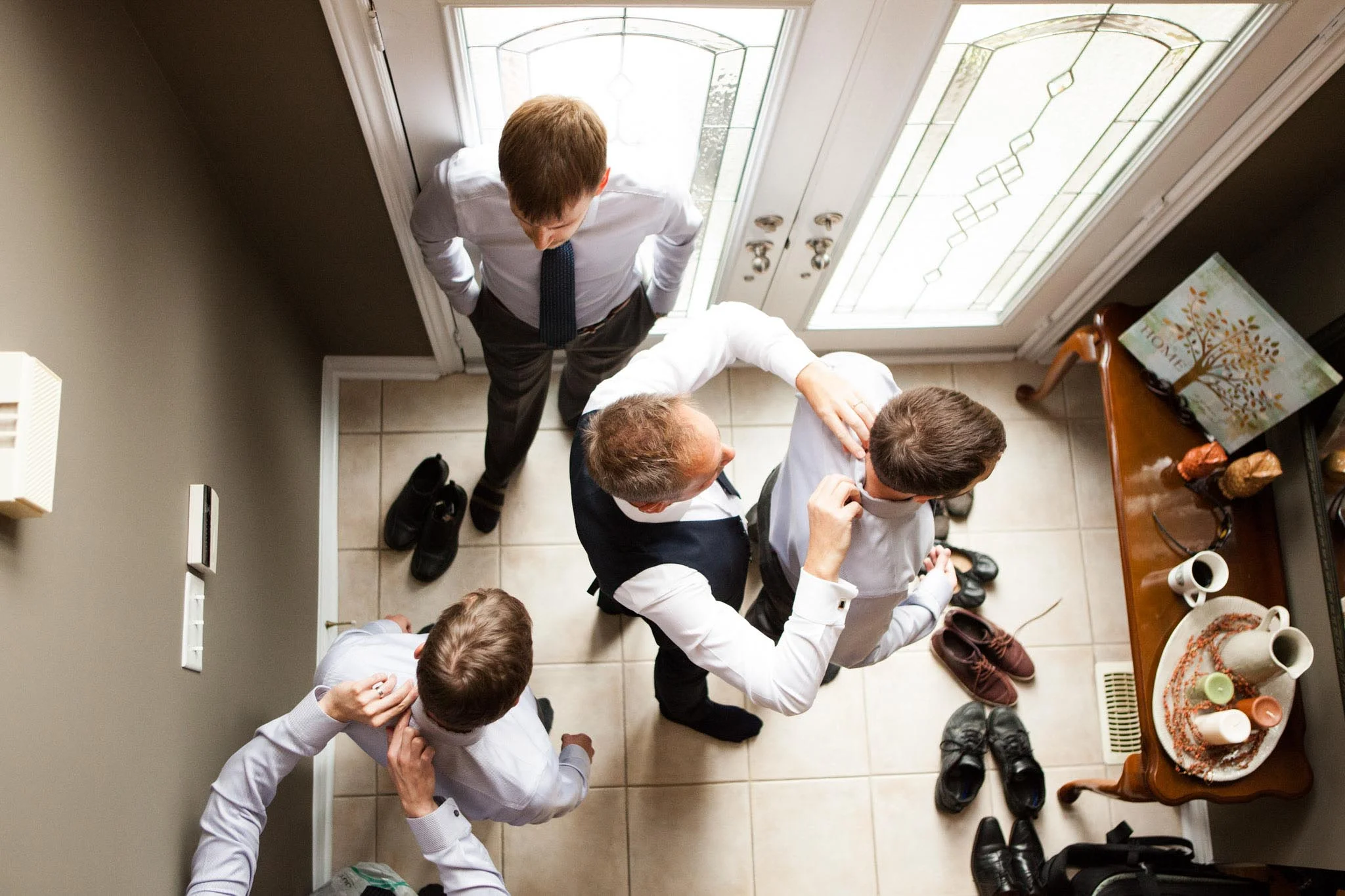 father of the groom helping groomsmen get ready for wedding day.jpg