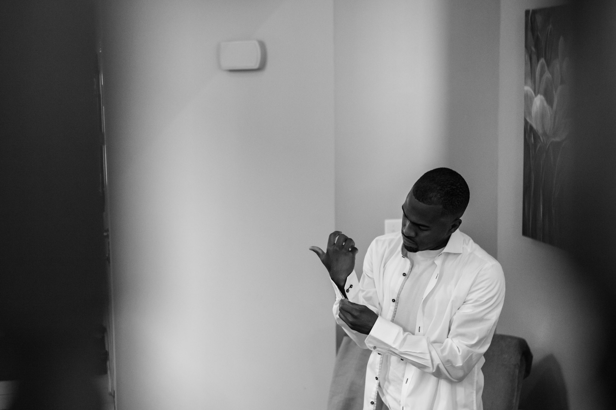 groom doing up cufflink getting ready for wedding black and white photography.jpg
