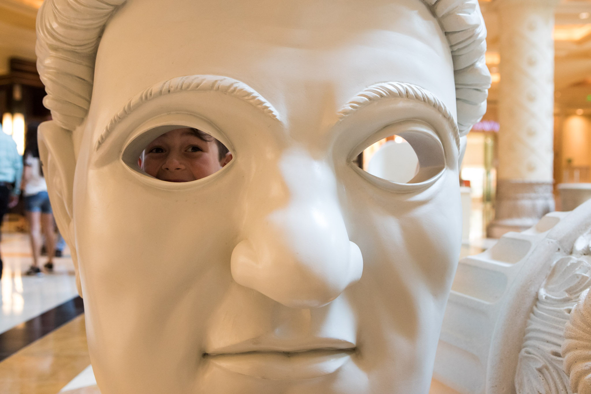 little boy peaking out eye socket of a large face statue.jpg