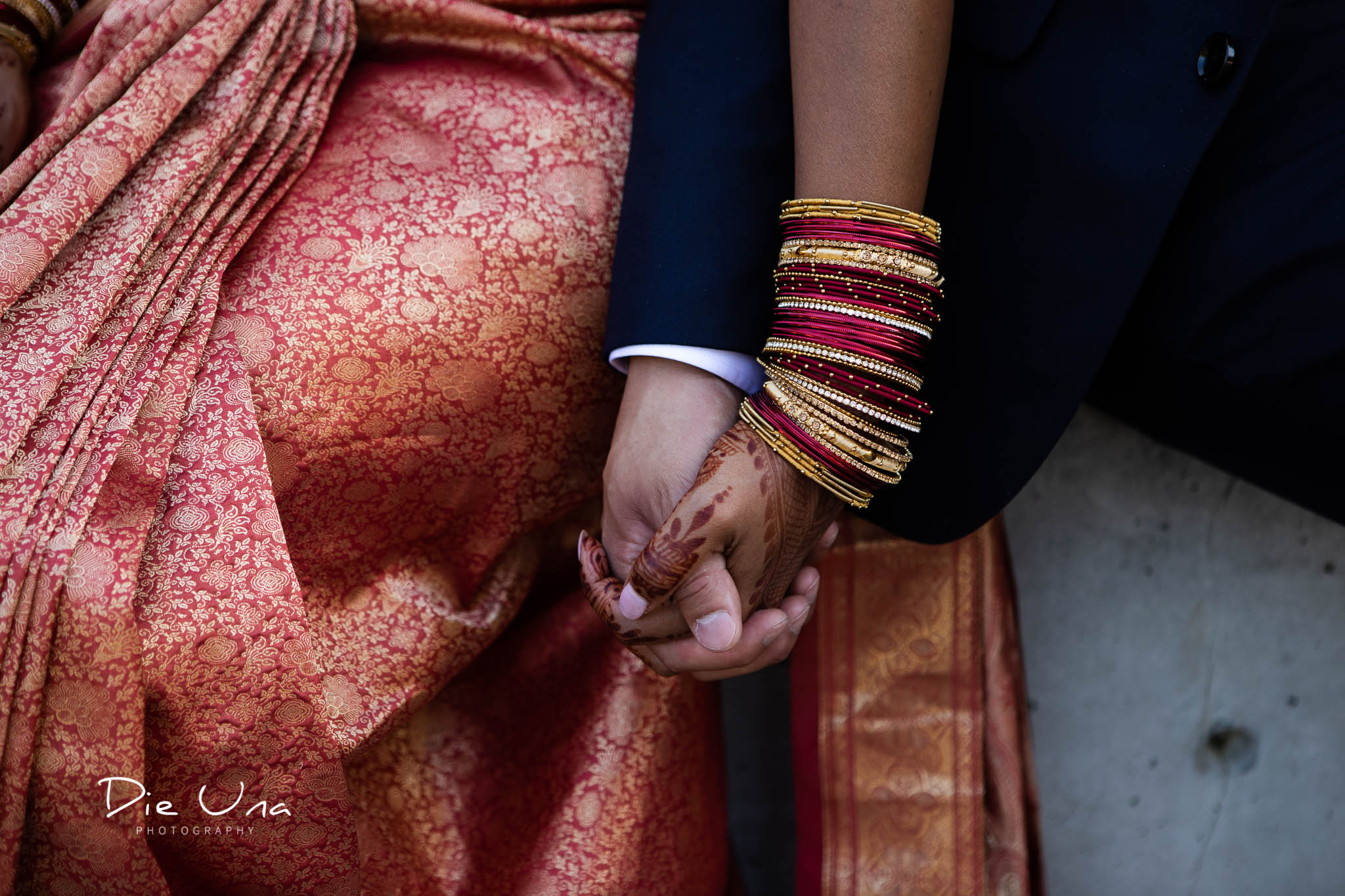 bride and groom holding hands bride wearing red and gold bracelets.jpg
