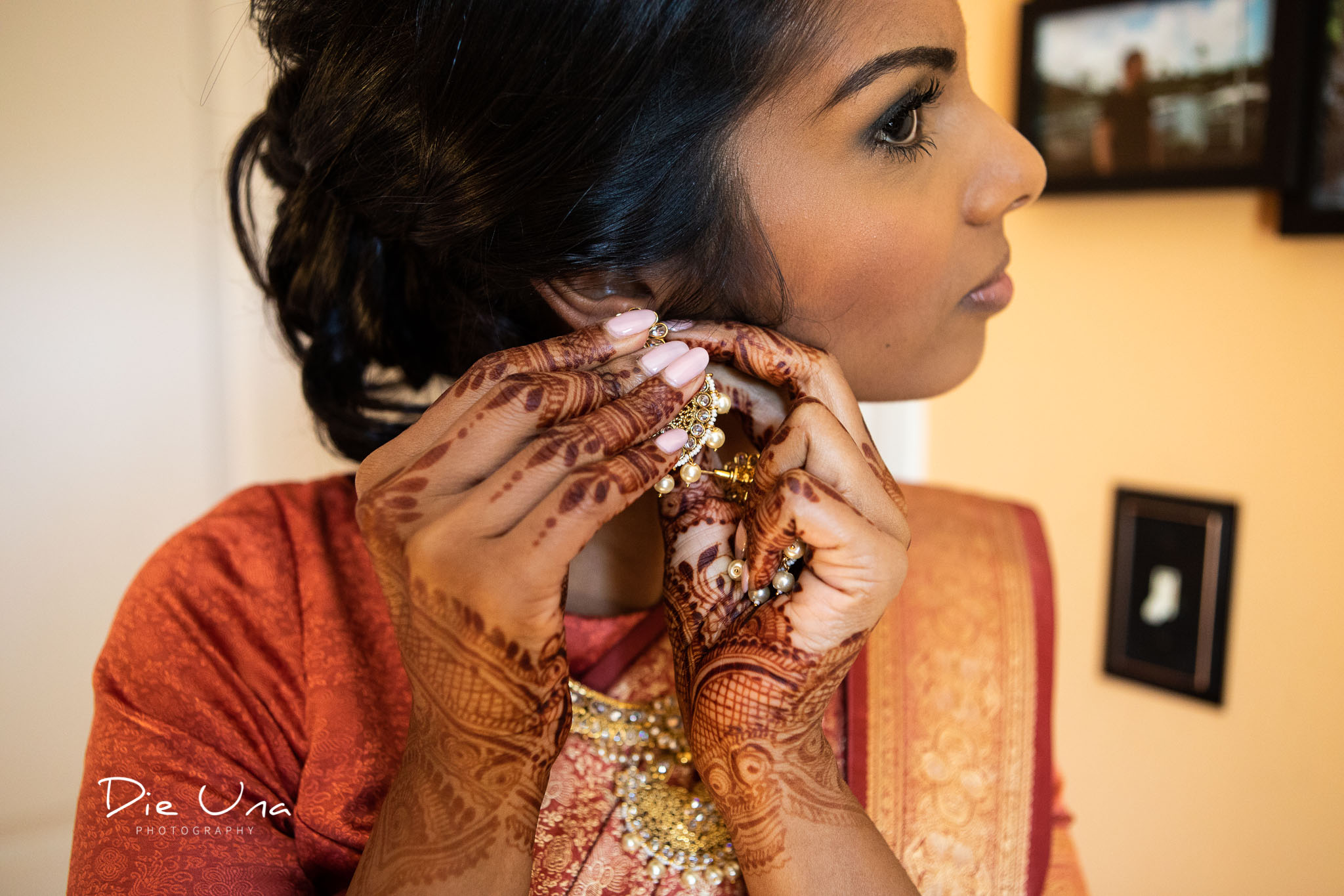 bride with henna tattooed hands putting on earrings.jpg
