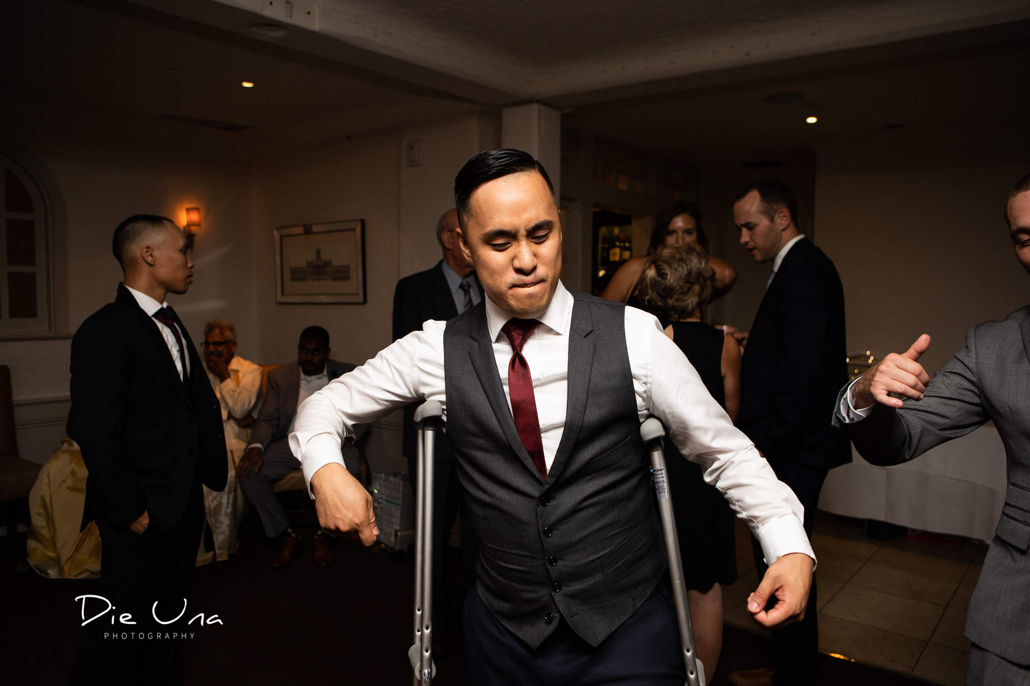 groom dancing during reception with crutches during wedding reception.jpg