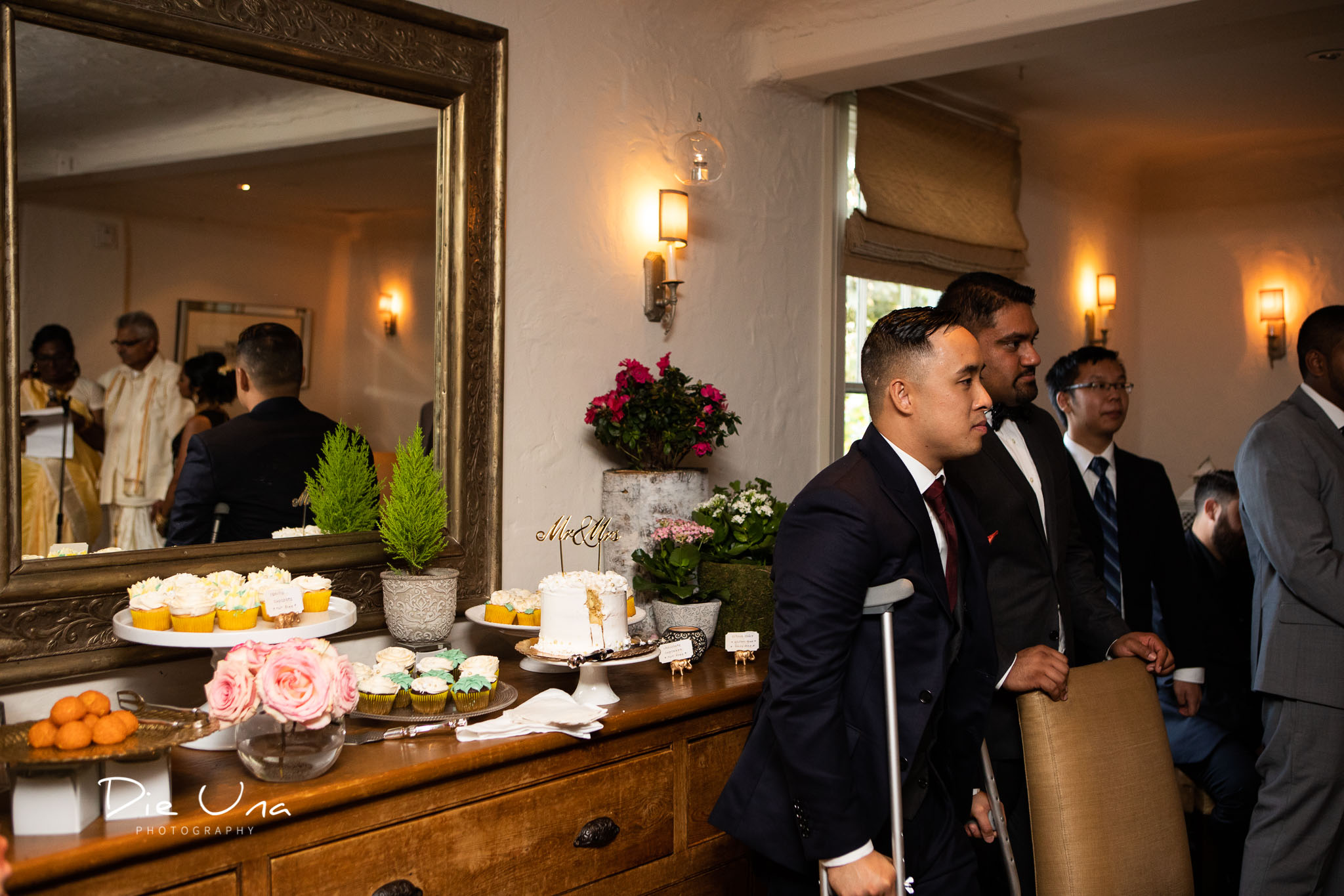 groom watching parents of the bride give a speech while they are reflected in a mirror.jpg